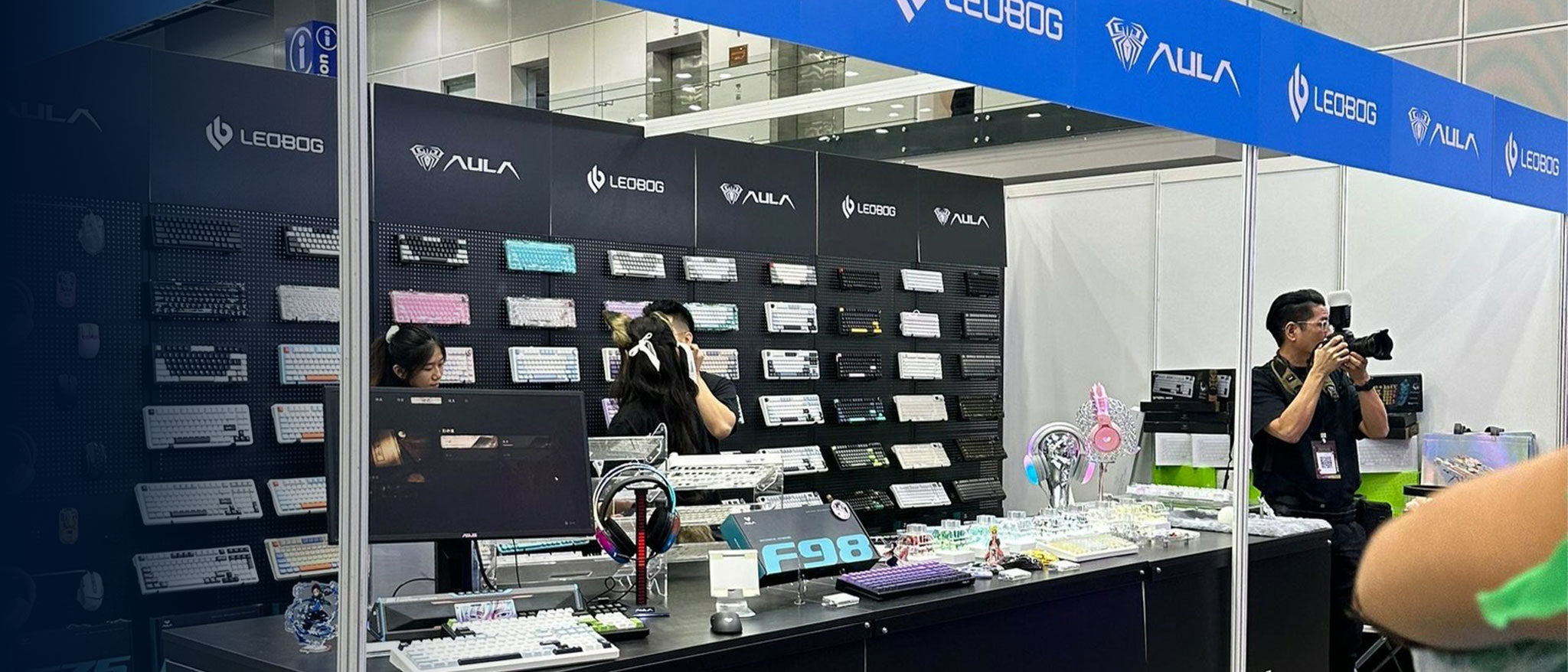 AULA and LEOBOG joint trade show booth display featuring a wall of mechanical keyboards, gaming mice, and peripherals at a technology convention.